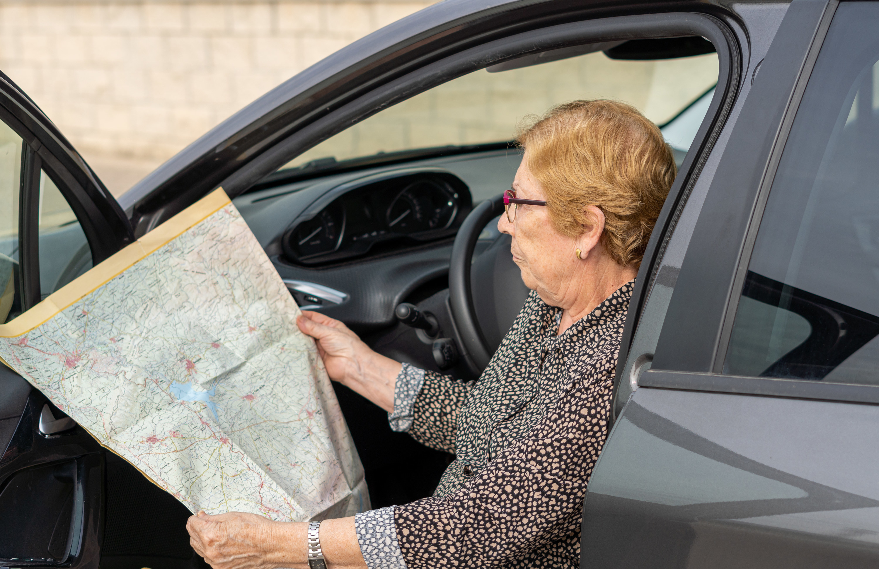 person sits in parked car, looking at a road map