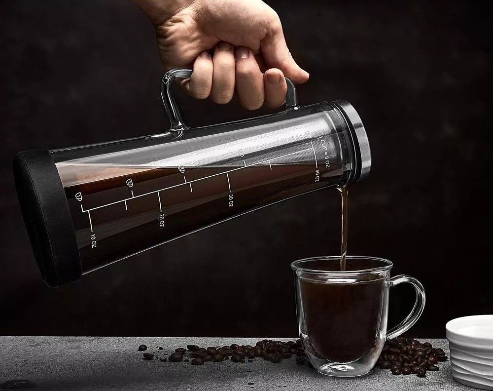 A model pouring coffee from coffee maker into a clear mug