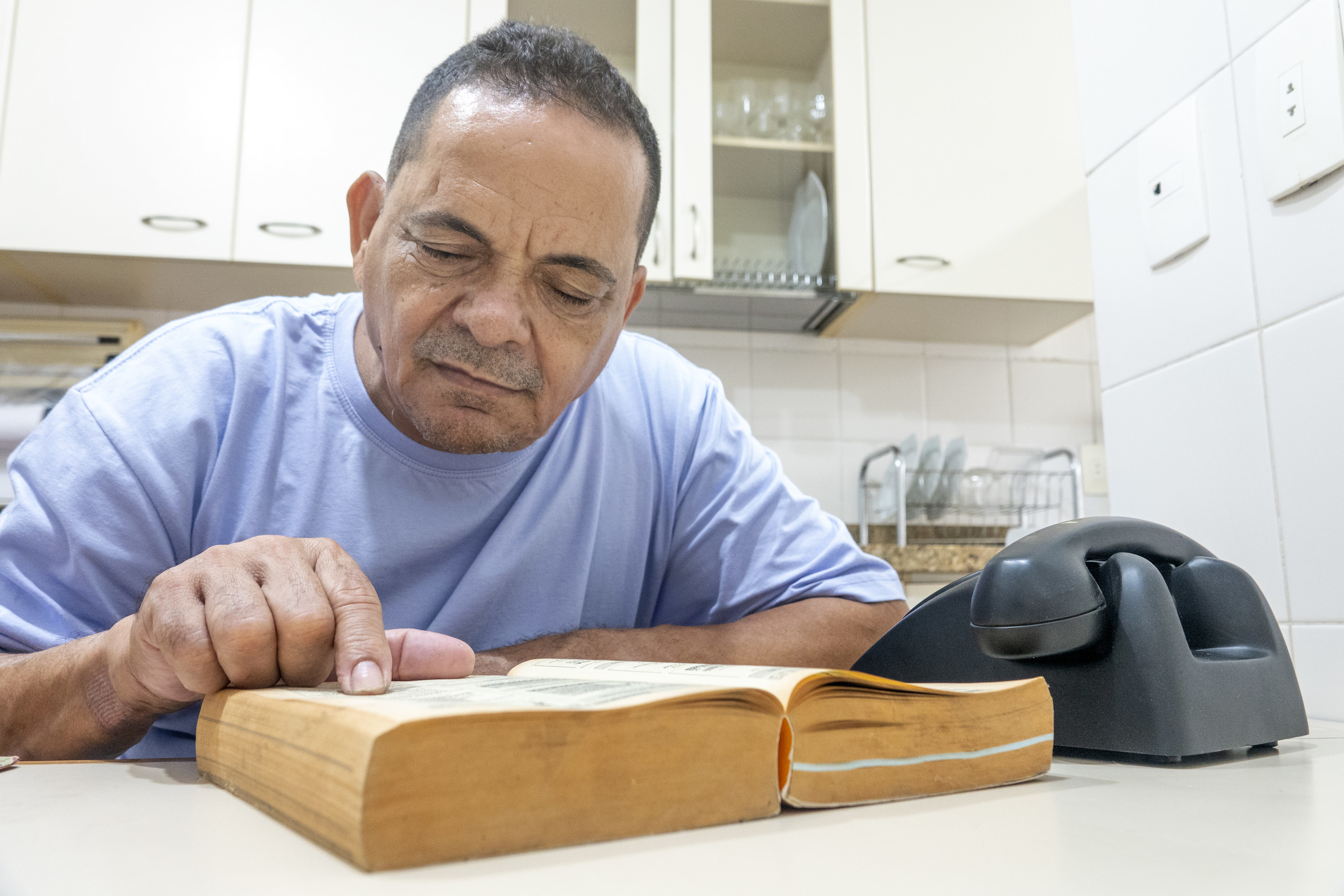 man reads though phonebook with a telephone on the table