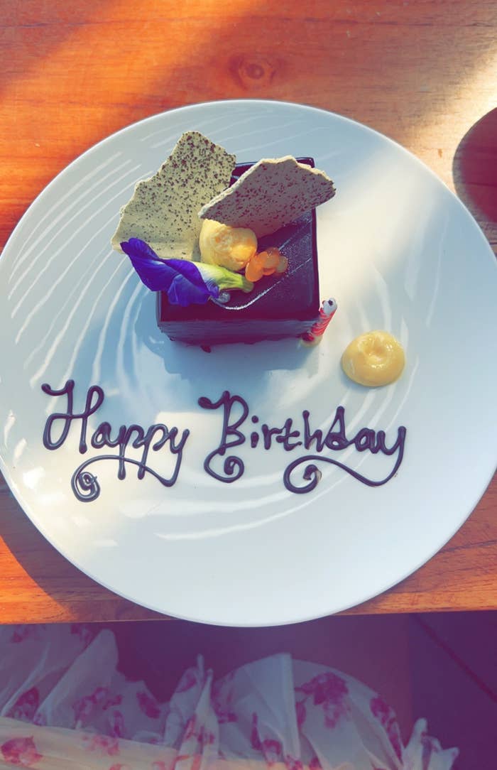 a small square of chocolate cake on a white plate that says &quot;Happy Birthday&quot;