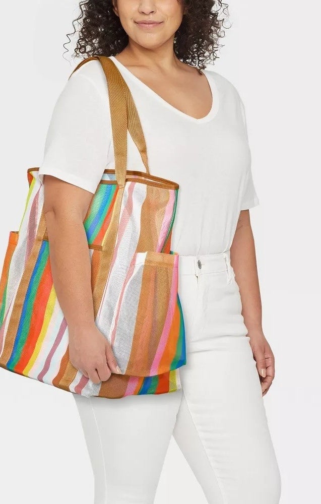 a model wearing all white with the stripped bag