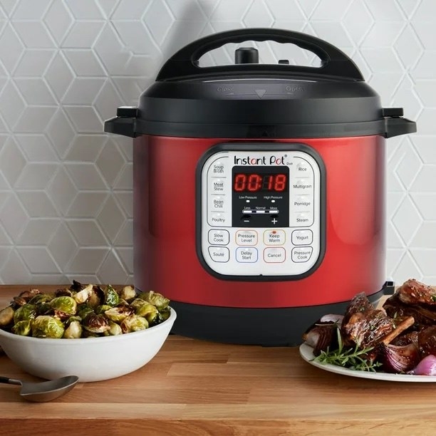 red instant pot with air fryer lid on a table next to plates of food