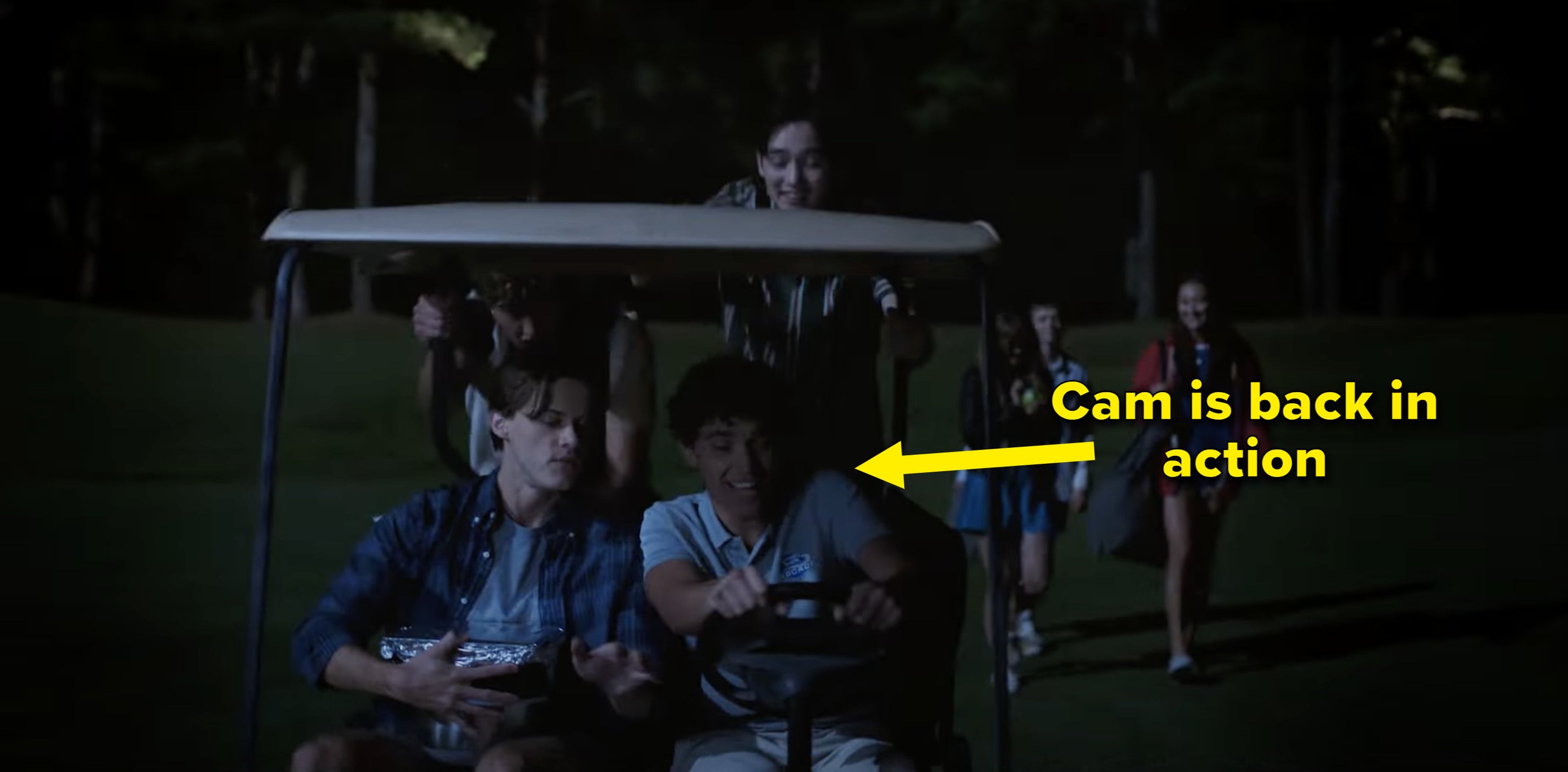 Cam driving two others in a golf cart at night