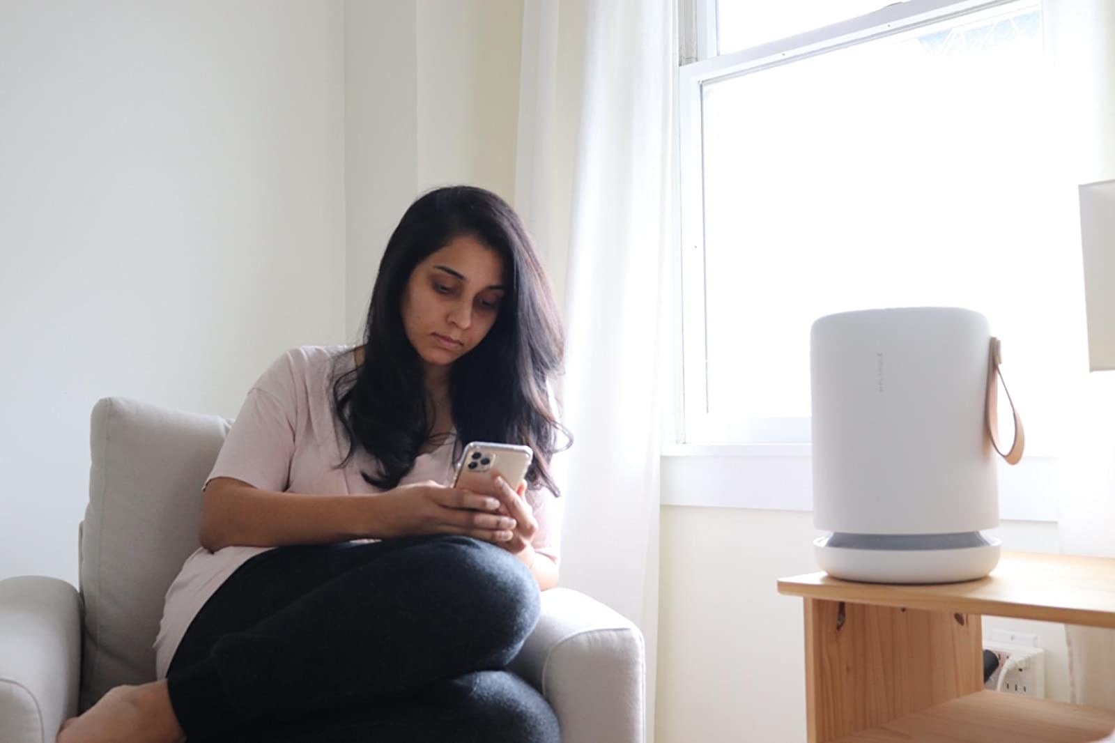 reviewer sitting in a chair next to their air purifier on a table