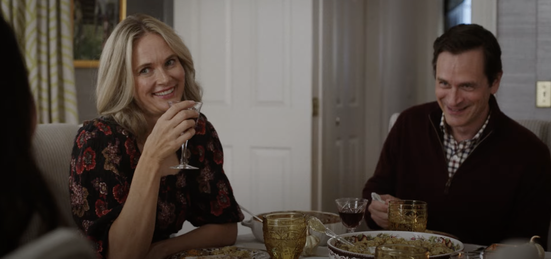 Susannah holding a drink as she sits at the dinner table