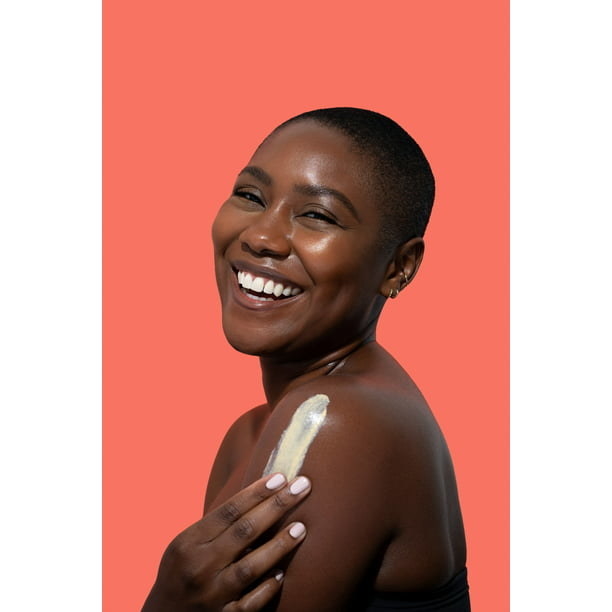 Model smiling while putting on the product in an orange backdrop