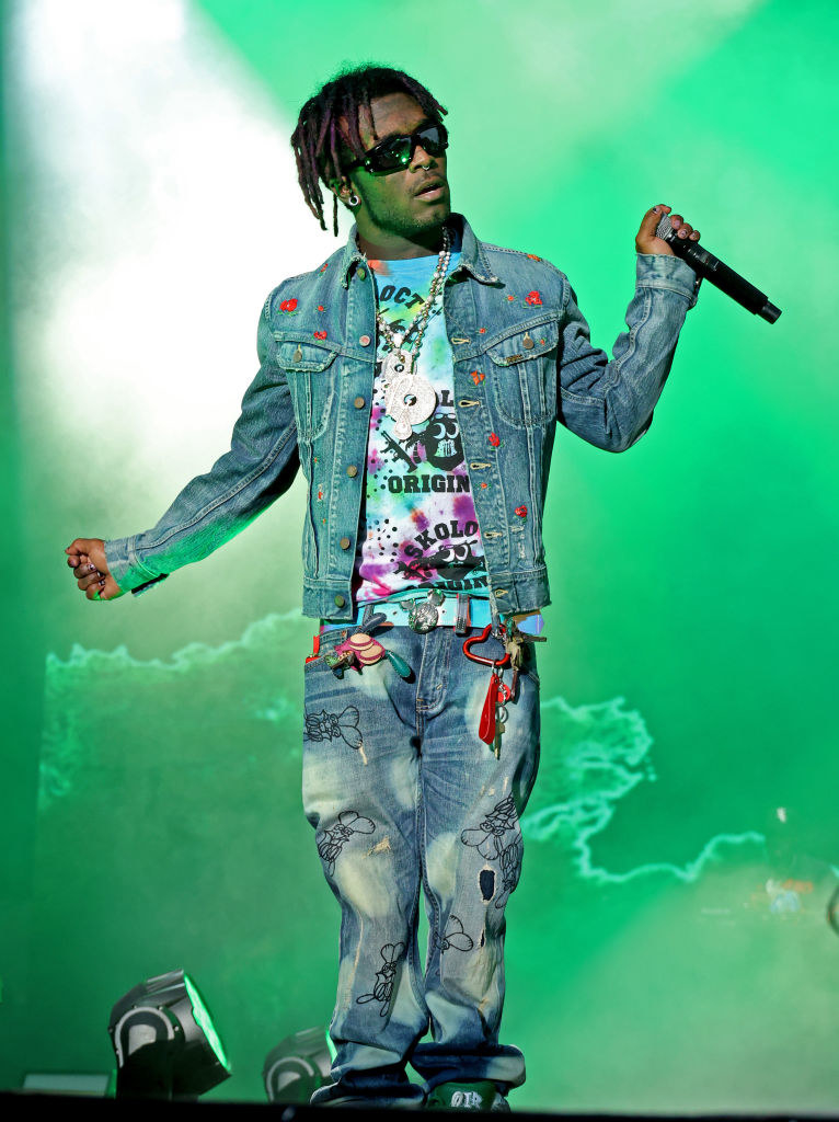 Lil Uzi Vert performing onstage and wearing loose jeans and a jean jacket
