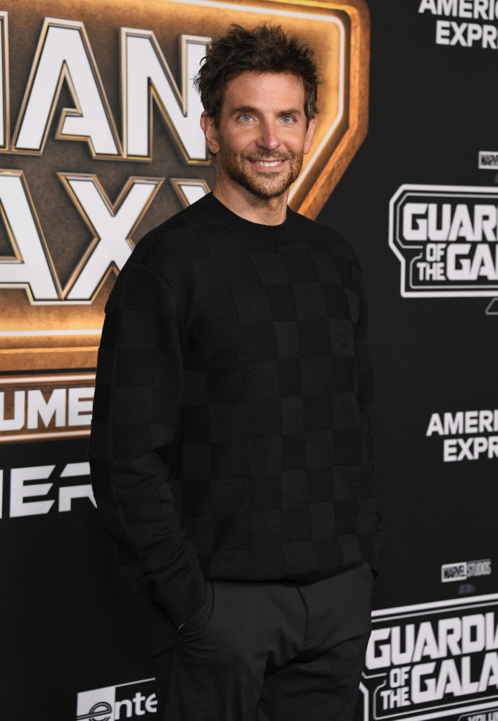 Bradley smiling and wearing pants and a crew-neck sweater