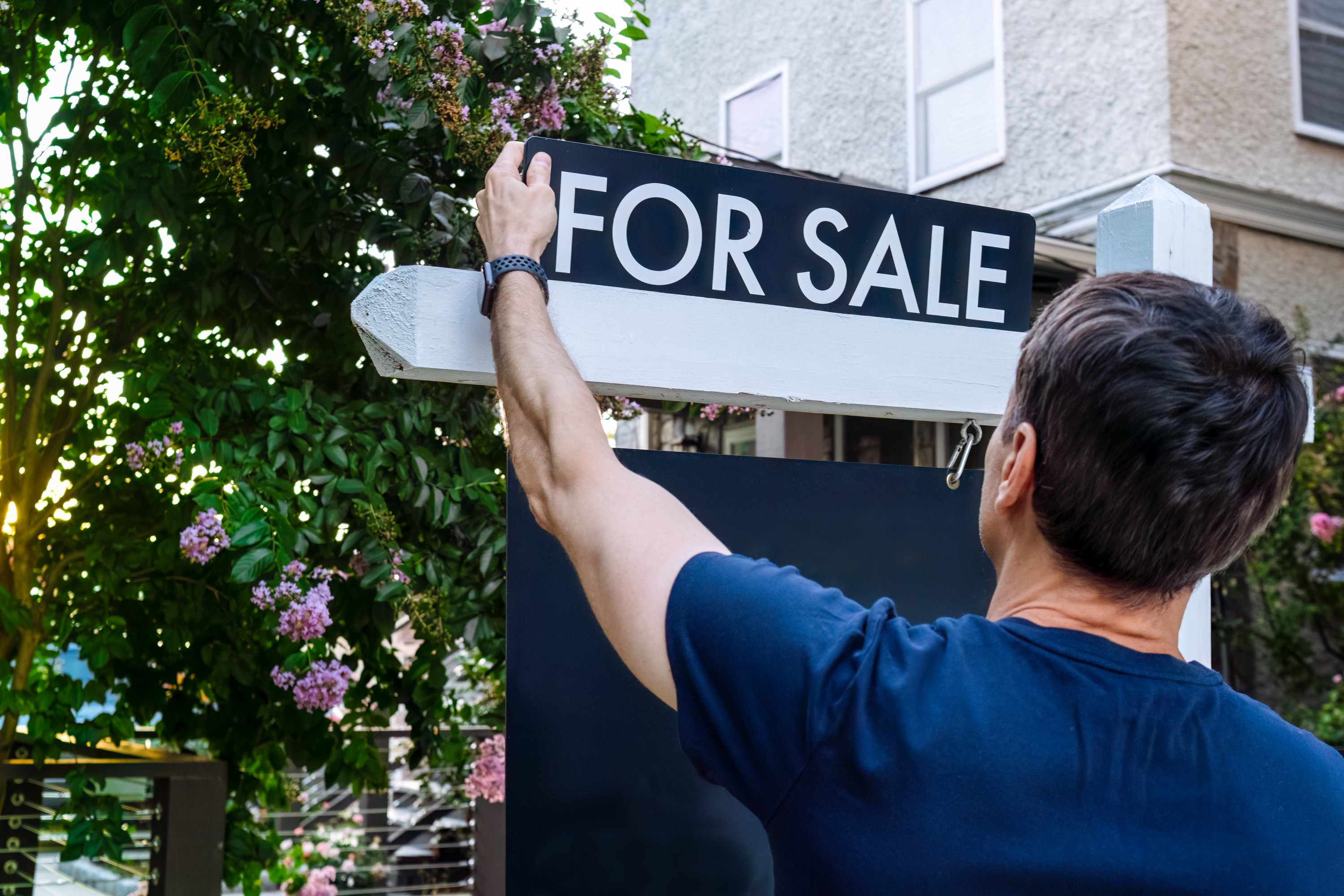 close-up of hands touching a "for sale" sign