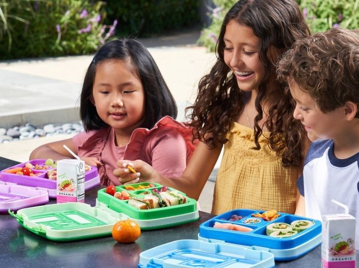 Kids eating lunch out of colorful bento boxes