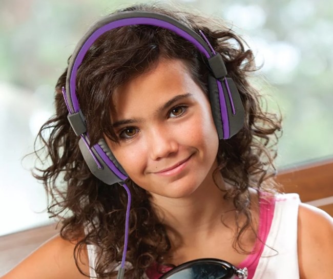 A smiling child wearing purple-and-black wired children's headphones