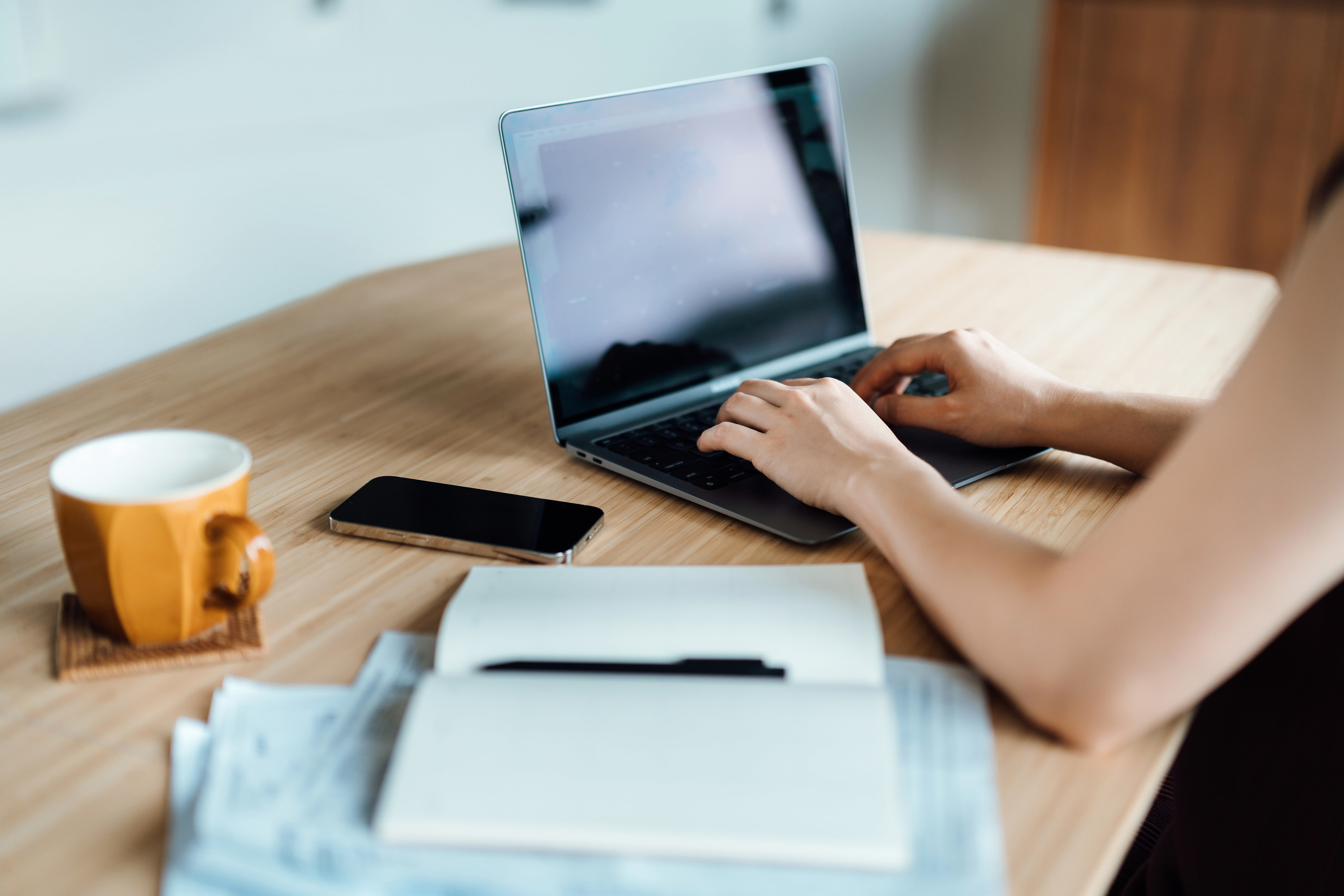 a hand typing on a laptop at a desk