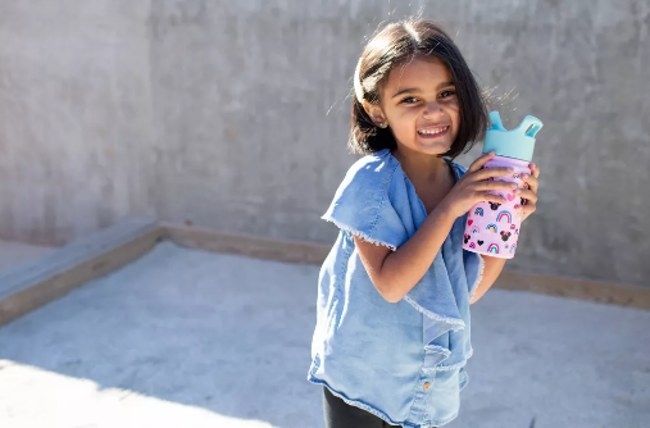 Child holding a pink water bottle in her hands