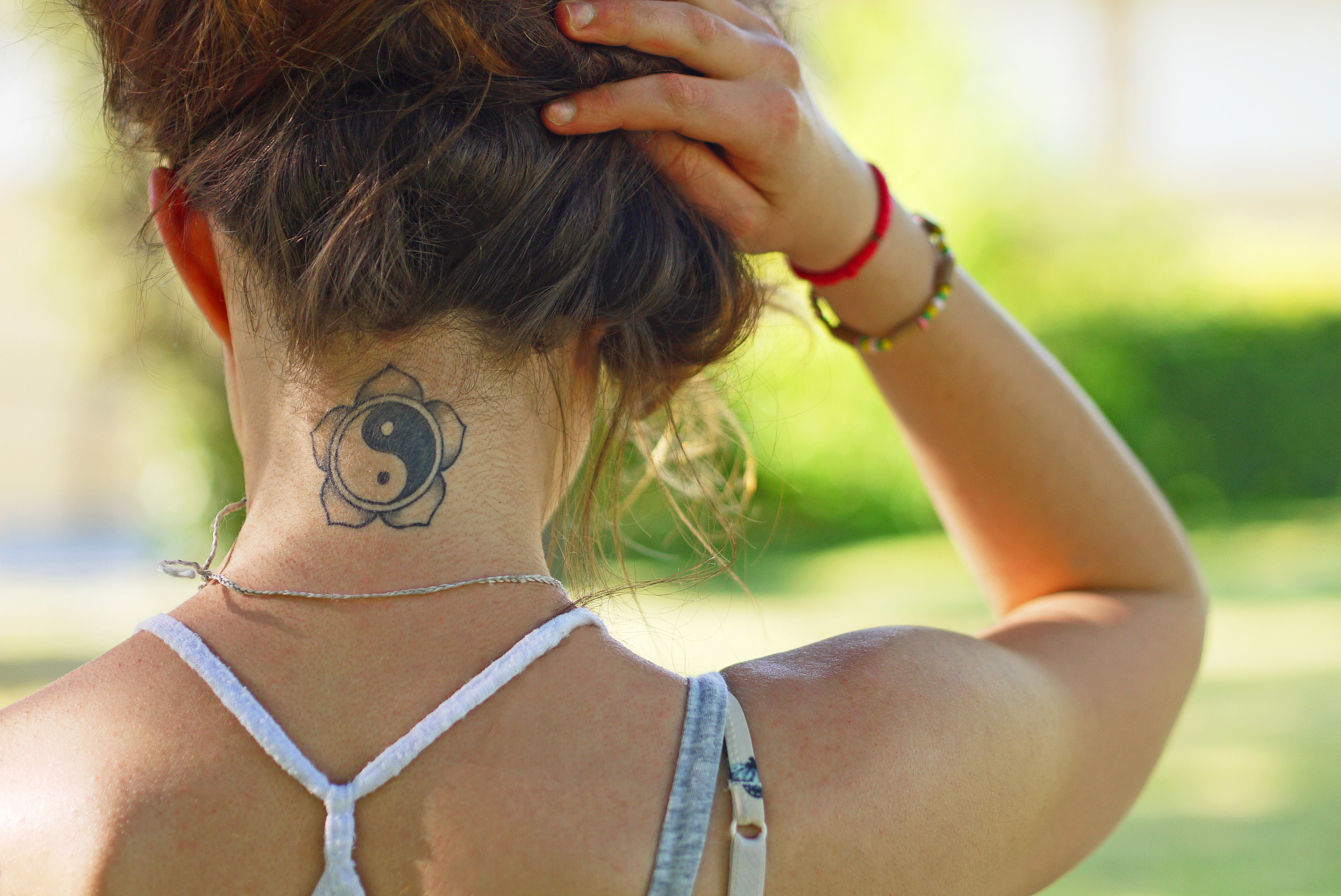 teen girl lifting up her hair to show off a tattoo on her neck