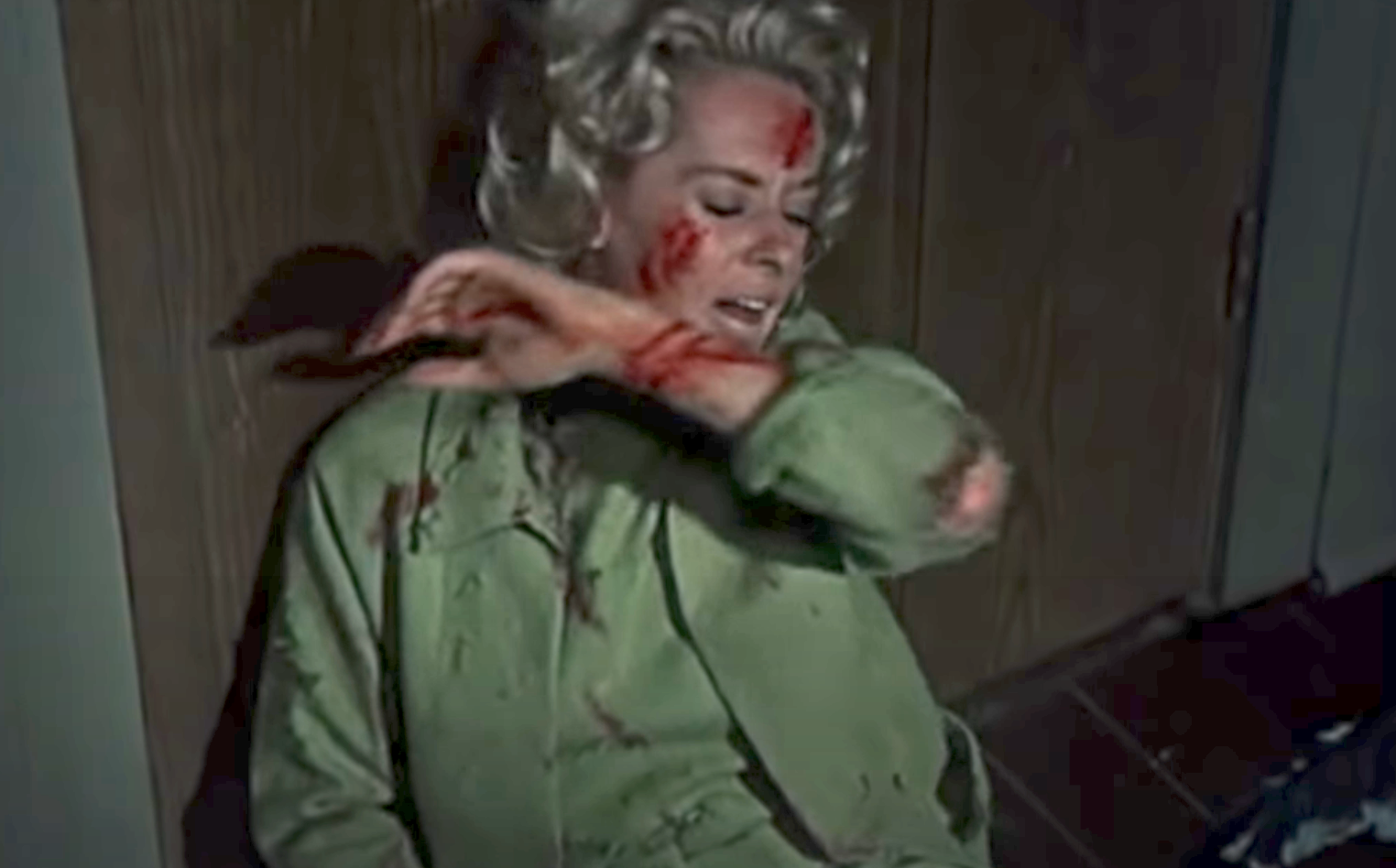 Hedren with a bloody face and arm held up to her face