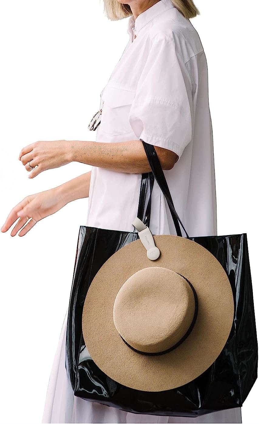 A model carrying a felt hat secured to a tote bag