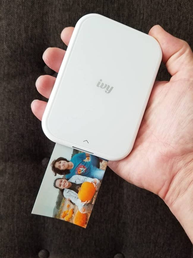 image of reviewer holding up the portable printer as it prints a photo