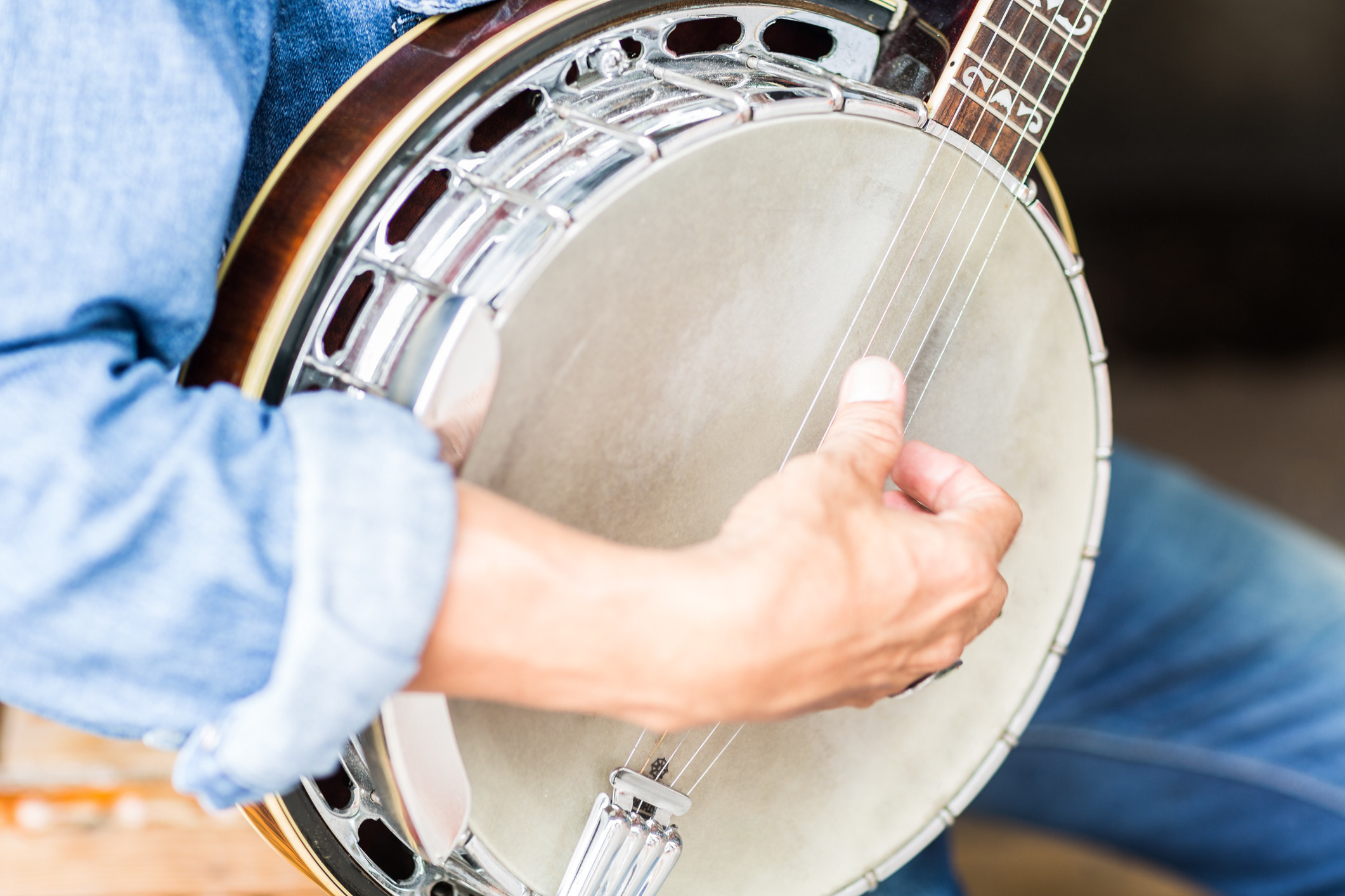 Closeup shot of a man&#x27;s hand strumming on a banjo.