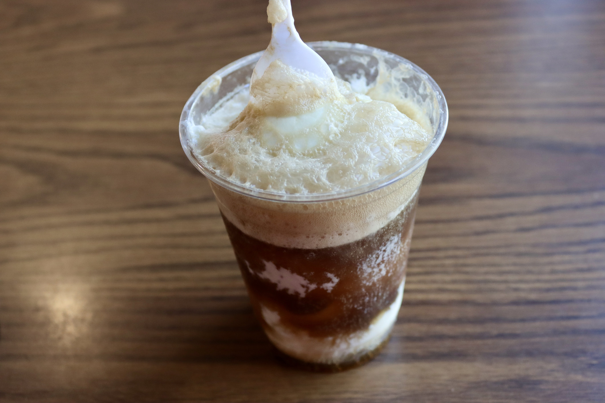 A root beer float in a plastic cup.