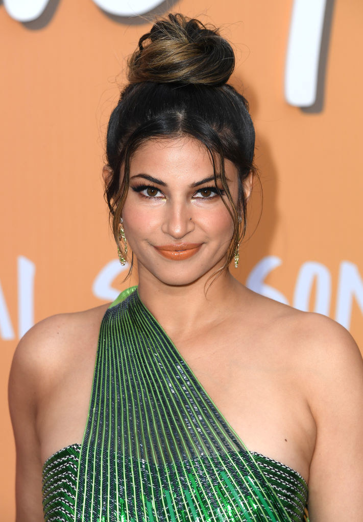 A close-up of Richa in a one-shouldered beaded outfit on the red carpet. Her hair is in a top-knot with wispy bangs