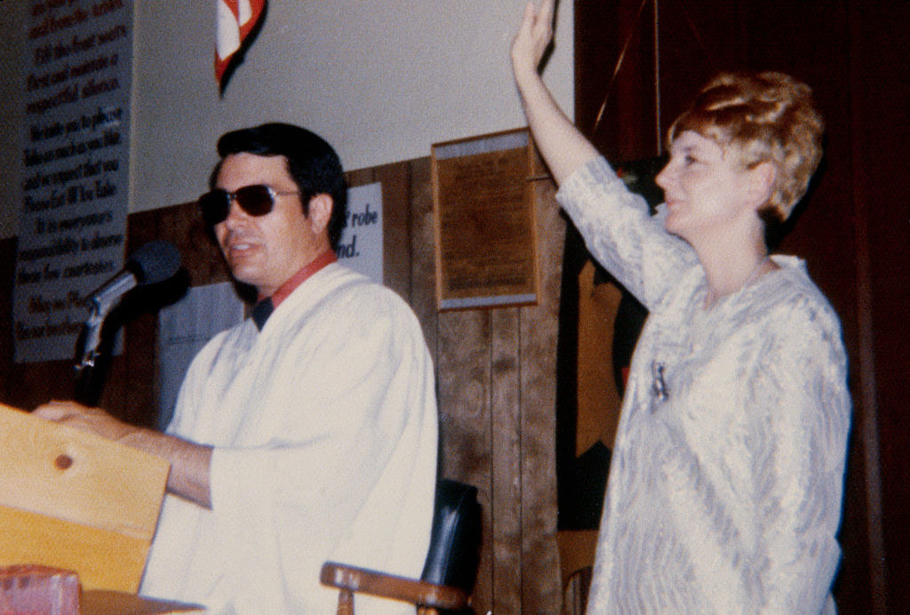 man at a podium while a woman stand beside with one arm lifted up