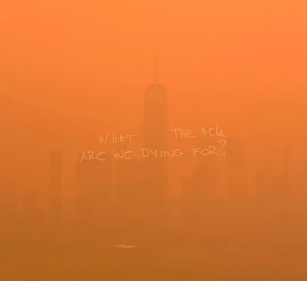 A barely visibly skyline due the smoke and haze with the words What The Hell Are We Dying For? written across the image
