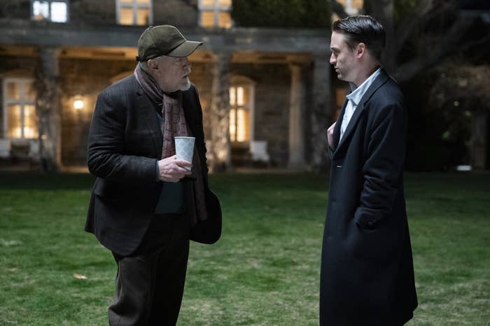 Logan and Roman Roy standing outside a mansion at night in a scene from Succession