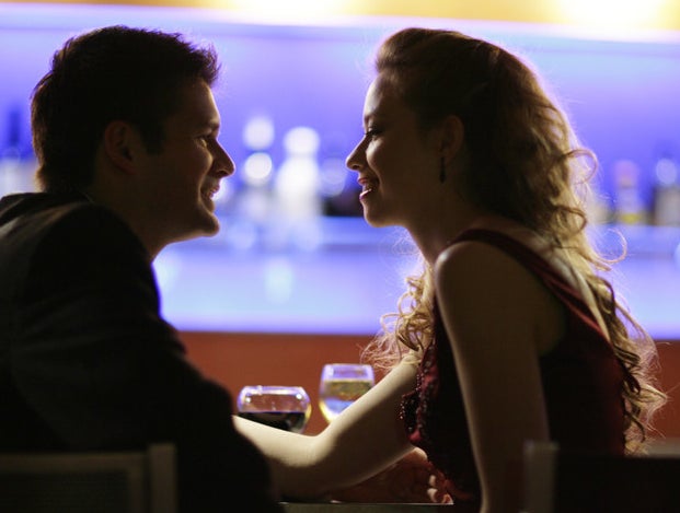A man and woman sitting at a bar and looking at one another