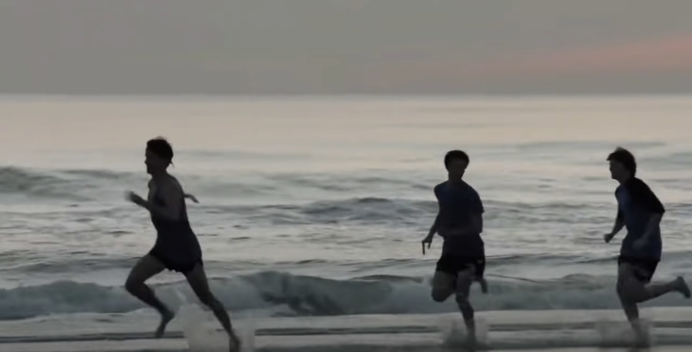 Three boys running at the beach