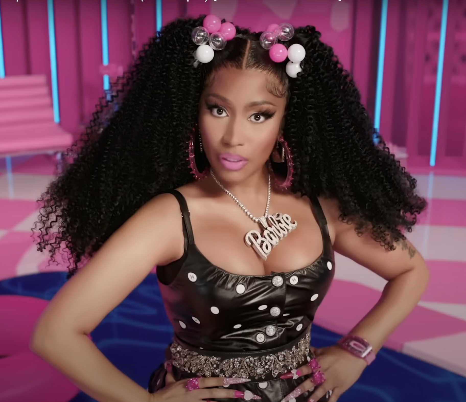 closeup of nicki wearing a large necklace with the barbie nameplate