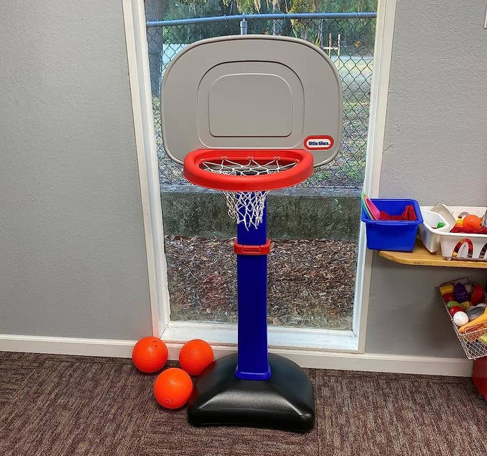 Reviewer&#x27;s photo of gray, red, blue, and black plastic basketball hoop with three ornage balls