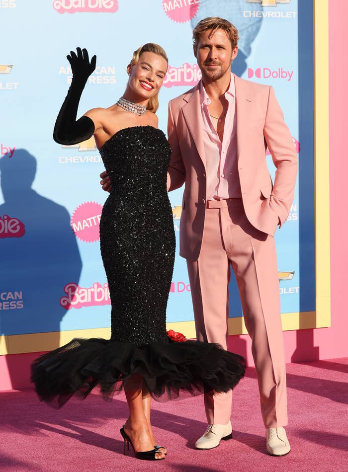 Margot waving at the cameras as she poses on the pink carpet with Ryan Gosling