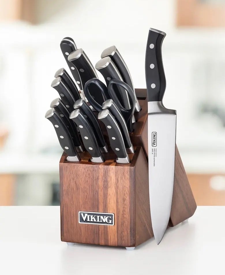 A brown knife block with black and silver blades, a chef&#x27;s knife is out