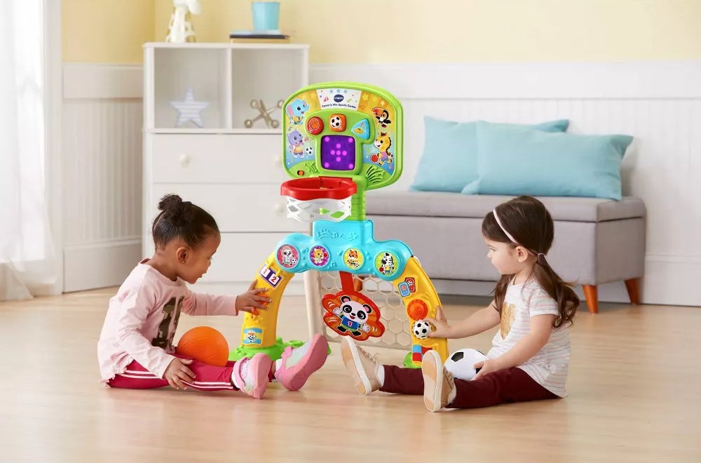 Two small children playing with brightly colored sport center toy