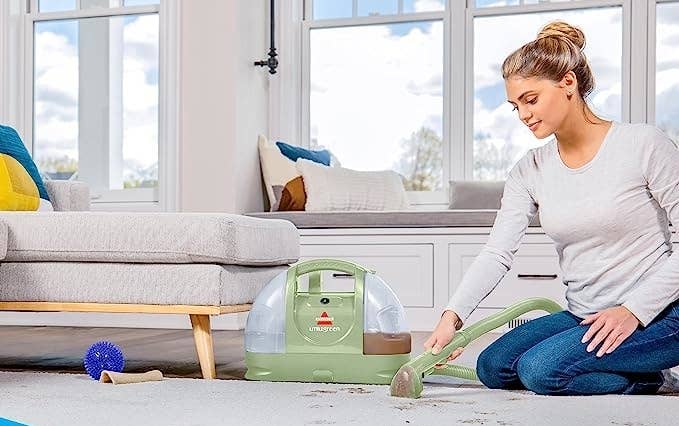 A model using the cleaner to remove muddy stains on a carpeted area