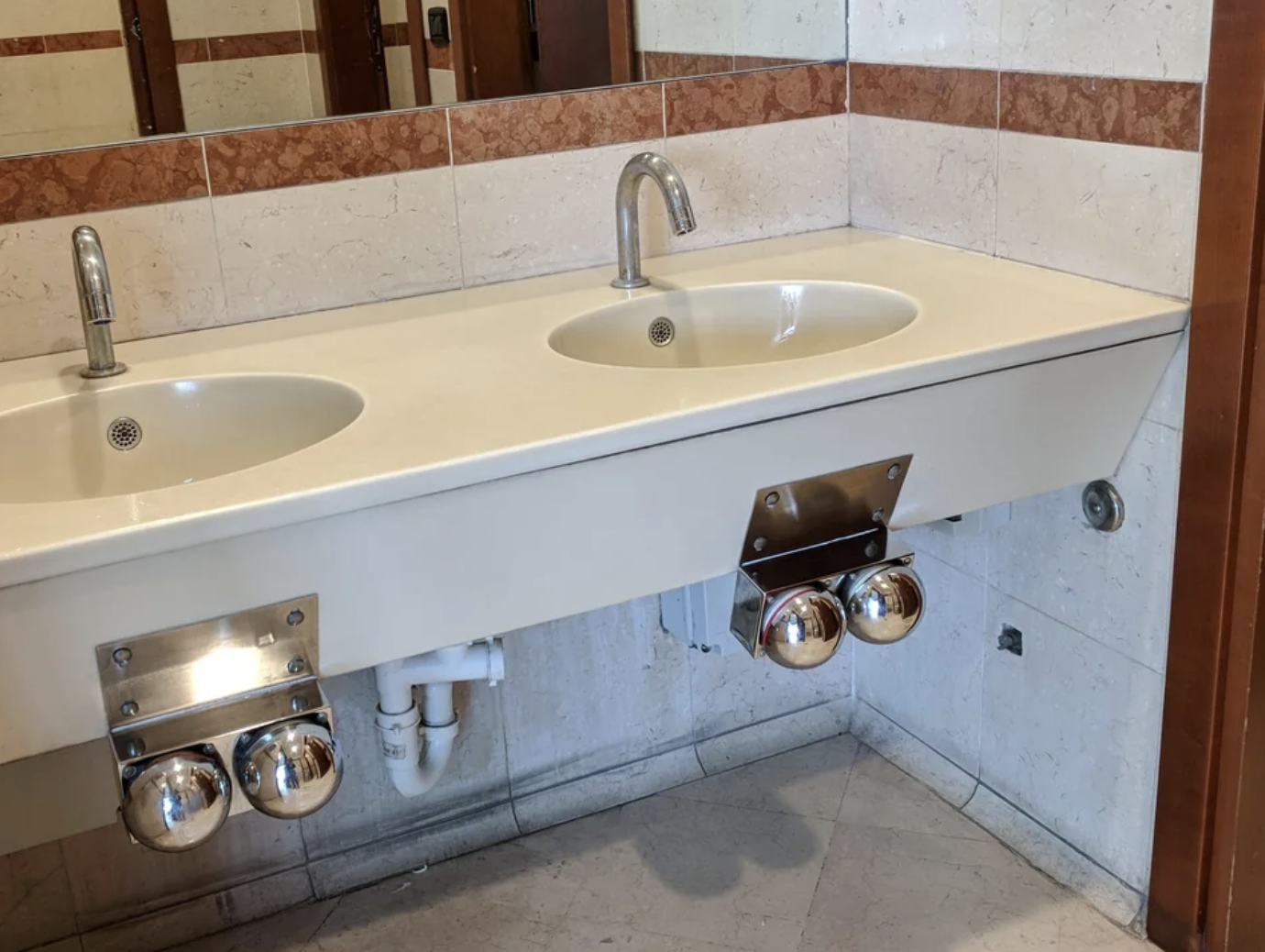 There is a metal square built into the sink at knee height with two buttons, one for hot water and one for cold. You press the button once to turn it on and again to turn it off