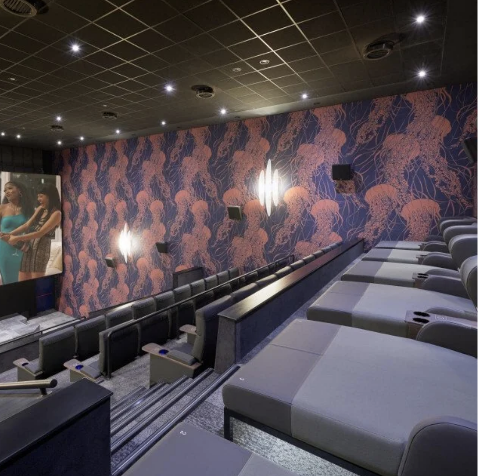 The movie theater has four rows, the first three of which are normal seats, and the last of which features long beds with raised pillows, so you can still see the screen