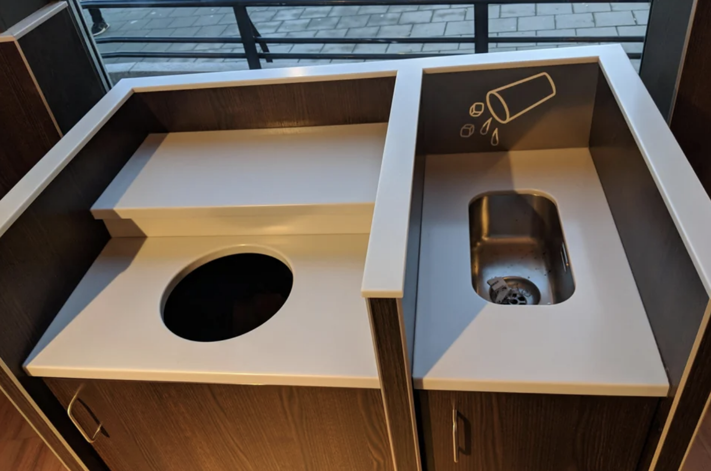 The trash can and mini sink are part of the same structure and are right next to each other for ease of use