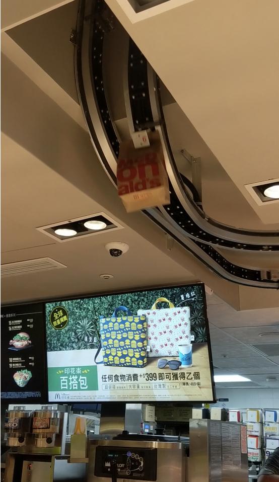The conveyor belt is attached to the ceiling, with bags of food hanging off it