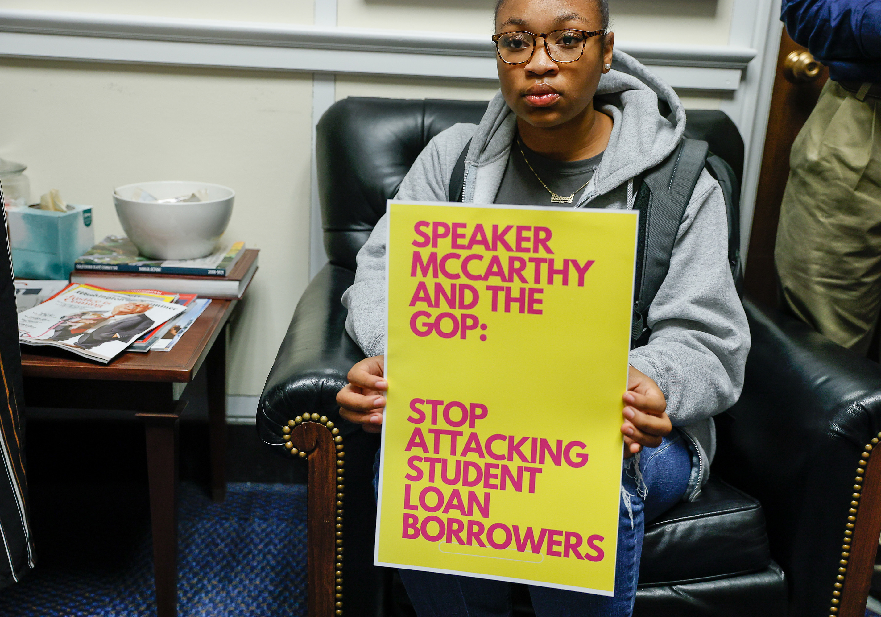 A man holding a sign that says, &quot;Stop Attacking Student Loan Borrowers&quot;