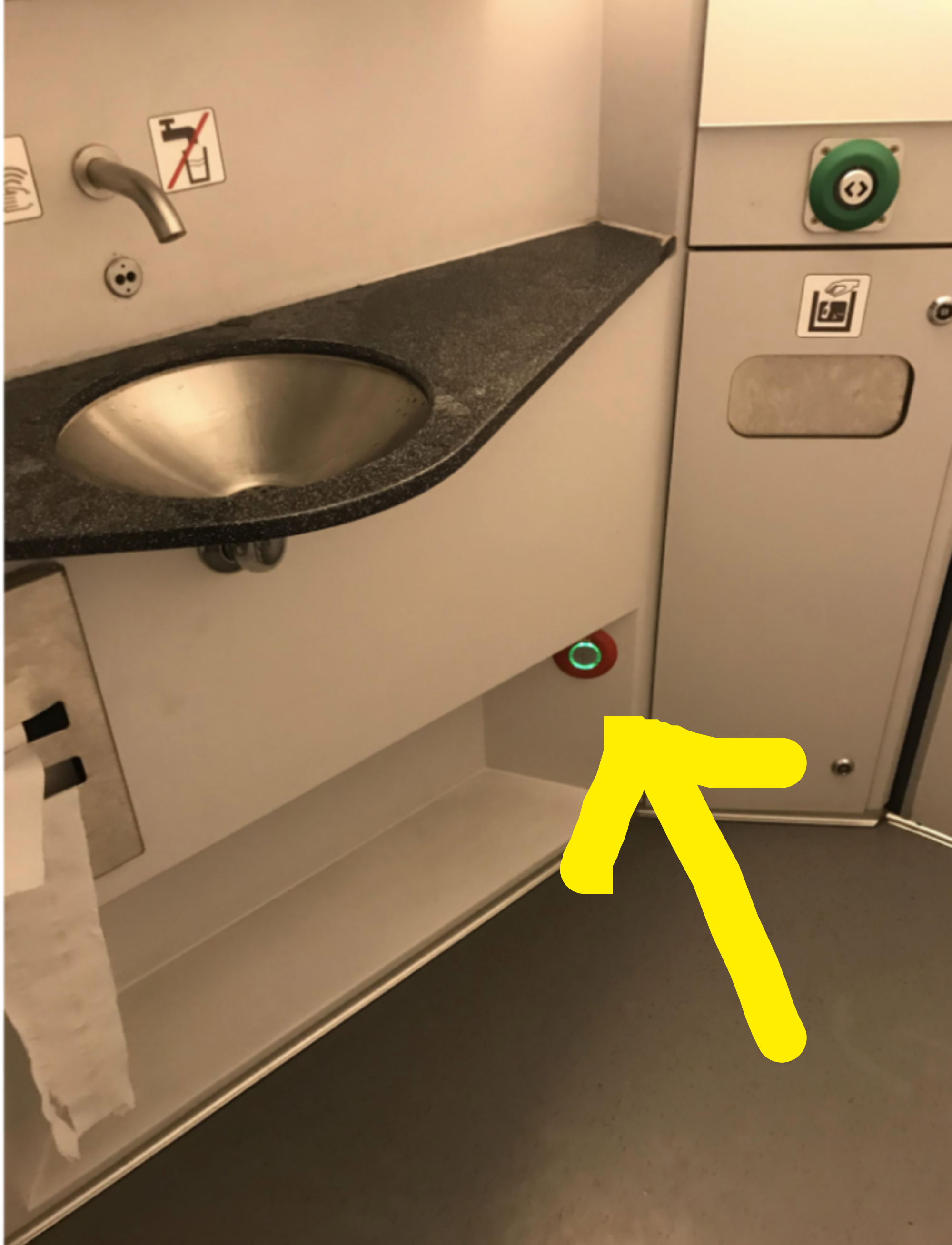 An arrow points out a button near the floor, hidden below the bathroom&#x27;s sink