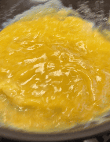 vigorously shaking the omelet to scramble the egg