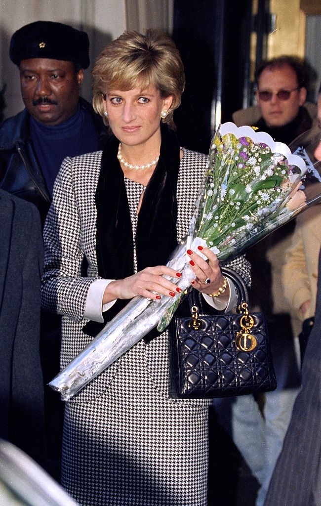 Diana holding the bag and a bouquet of flowers
