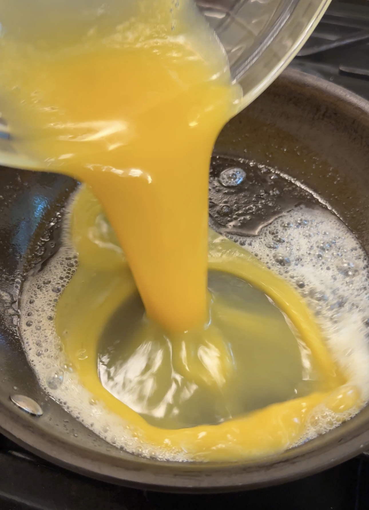 pouring beaten eggs into skillet with melted butter