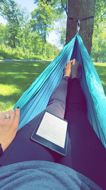 another reviewer relaxing in a hammock with their kindle