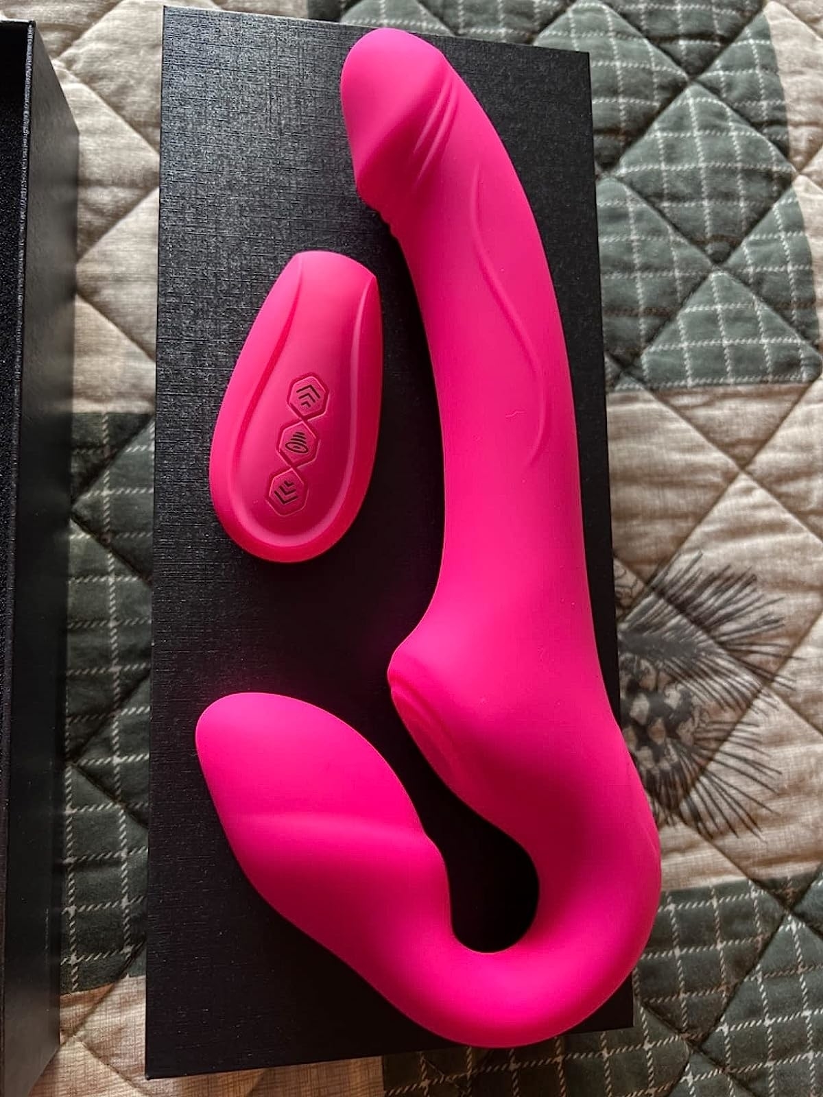 Pink strapless strap-on next to wireless remote