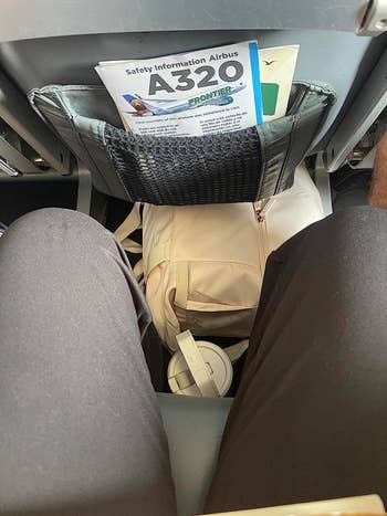 reviewer's beige bag under an airplane seat