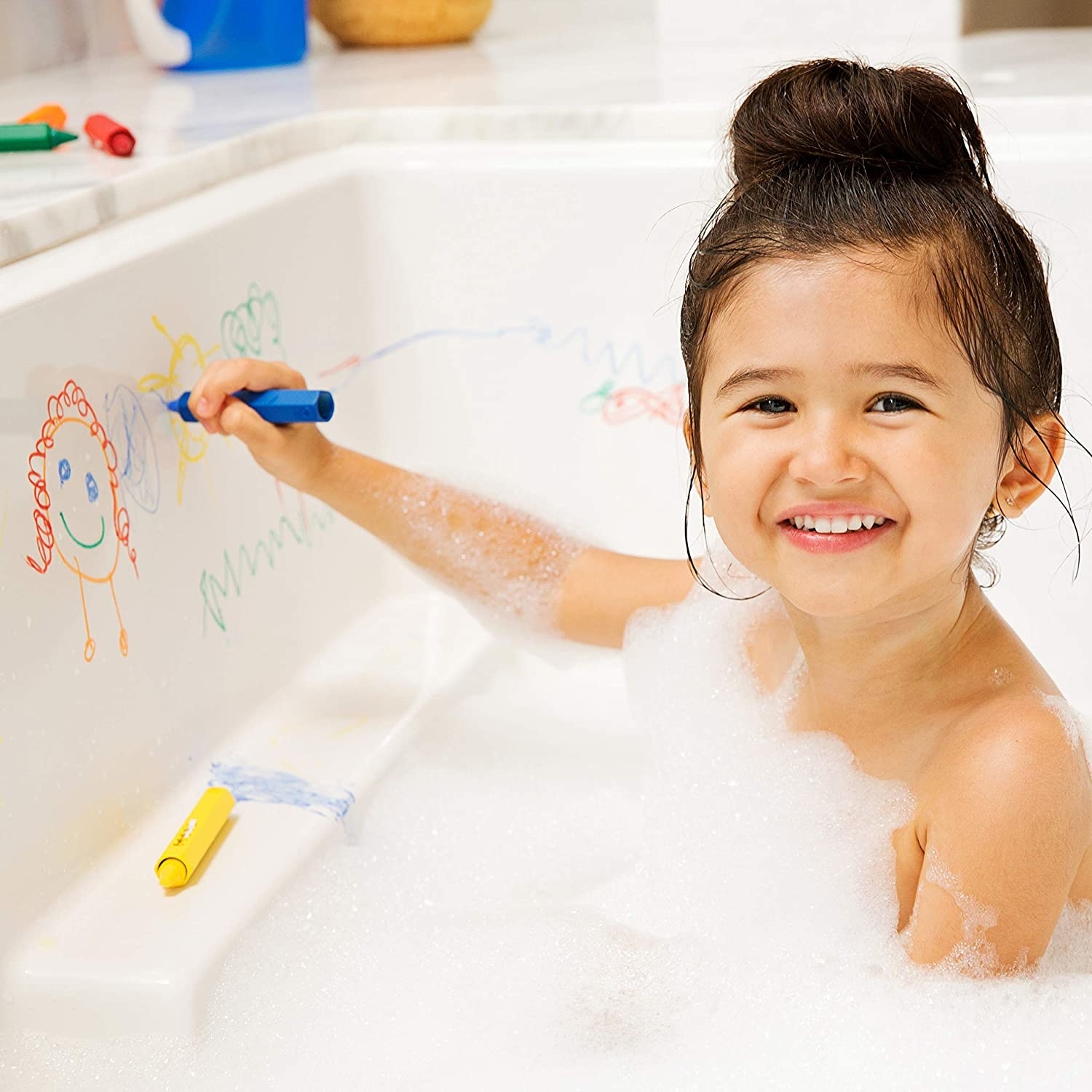 child drawing on edge of bath tub while having a bubble bath