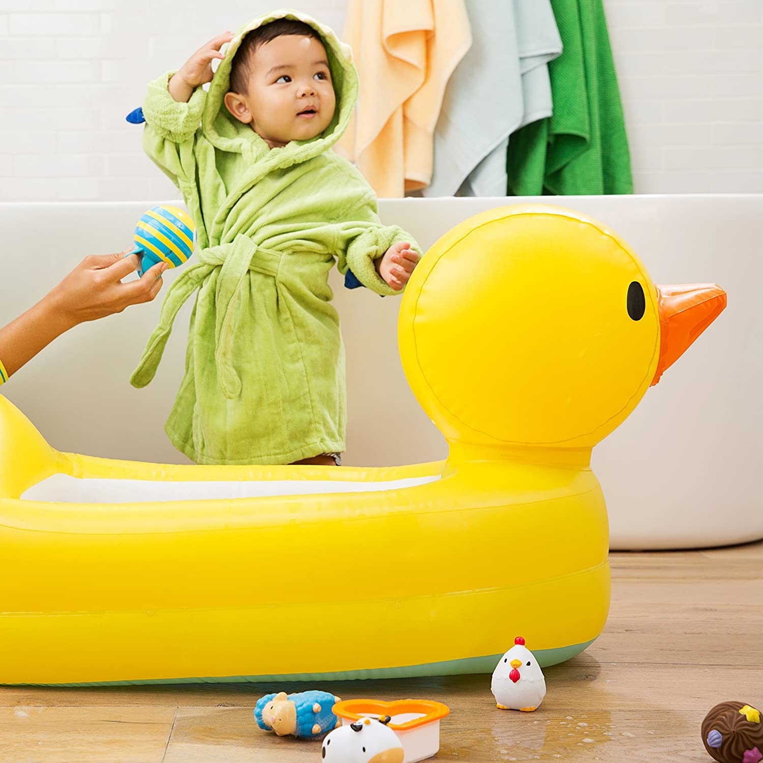 child in robe standing beside ducky tub in bathroom