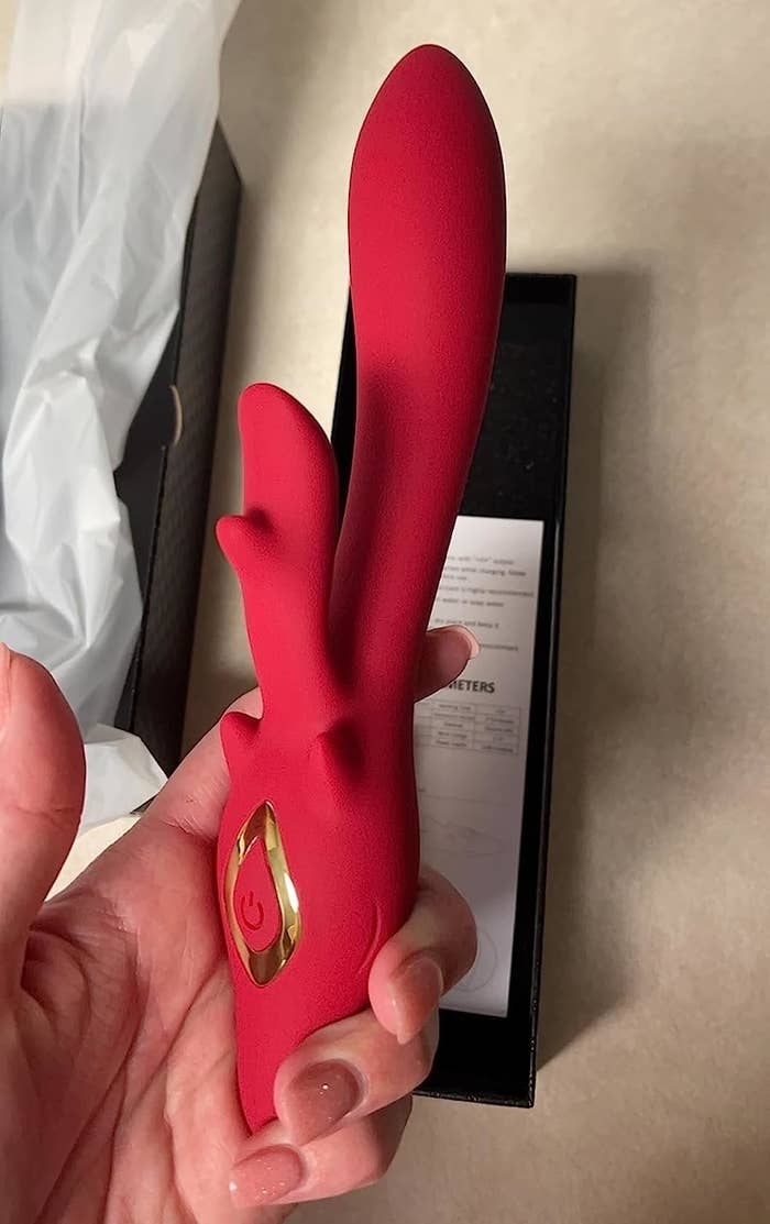Reviewer&#x27;s hand holding red rabbit vibrator